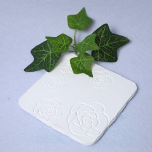 Base de gesso com padrão de camélia em relevo, ideal para velas, copos, perfumes ou pequenos arranjos decorativos. Design elegante e sofisticado, perfeito para realçar a decoração e proteger superfícies.