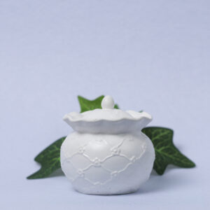 Pote de gesso com padrão em losango e flores nos vértices, com tampa inspirada em elementos culturais e antigos, ideal para armazenamento e decoração.
