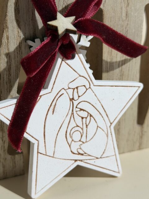 “Enfeite natalino artesanal em forma de estrela com ilustração da Sagrada Família gravada em madeira, detalhe em laço de veludo e estrela decorativa – ideal para decoração de Natal com significado religioso e estilo minimalista”