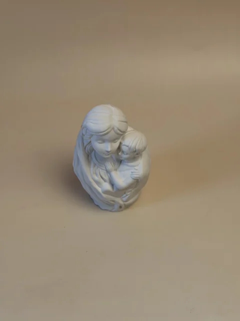Figura branca de Maria com o Menino ao colo, vista de cima, com as cabeças juntas e o manto em relevo.