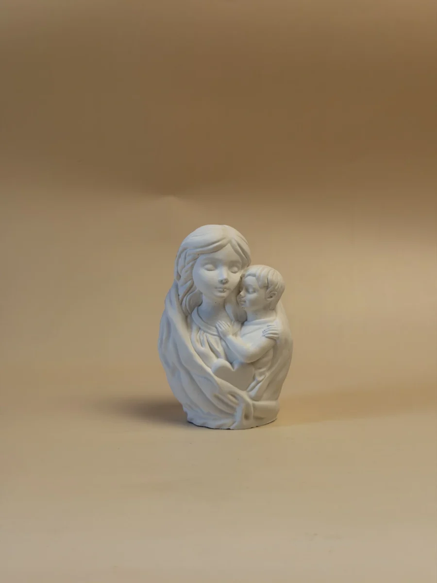 Figura branca de Maria com o Menino ao colo, com os rostos e as pregas do manto em relevo, vista em perspetiva.