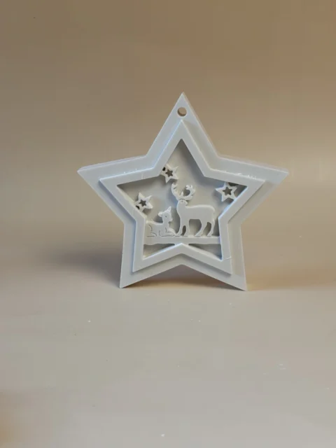 Pendente branco em forma de estrela de Natal, com renas e pequenas estrelas recortadas no centro, visto de frente.