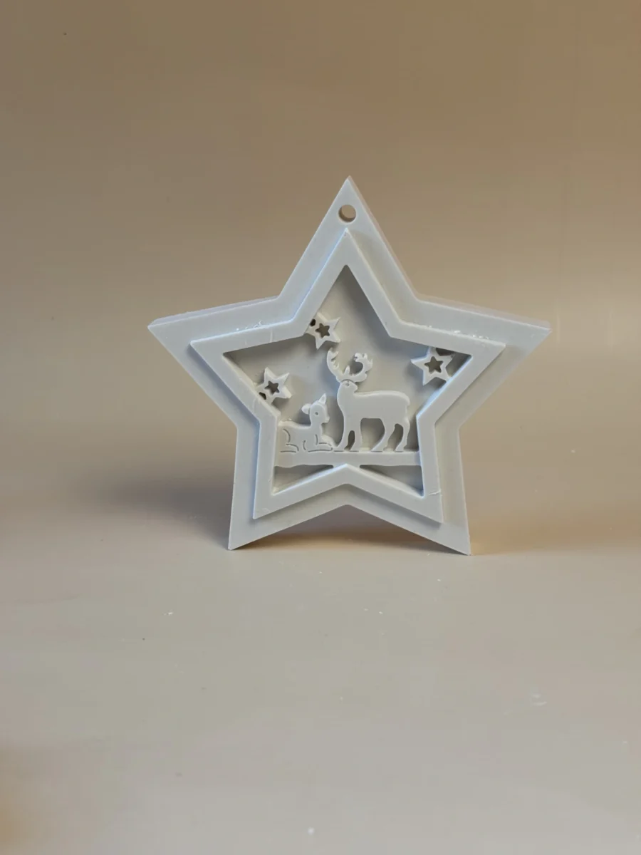 Pendente branco em forma de estrela de Natal, com renas e pequenas estrelas recortadas no centro, visto de frente.