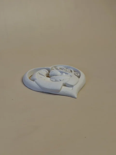 Pendente Sagrada Família branco em forma de coração, visto de lado, com o relevo das figuras em destaque.