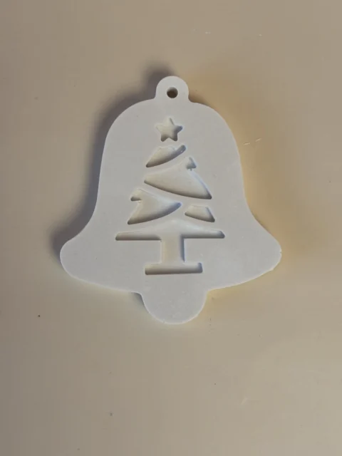 Pendente branco em forma de sino, com motivo de árvore de Natal, estrela e pequeno orifício para pendurar.