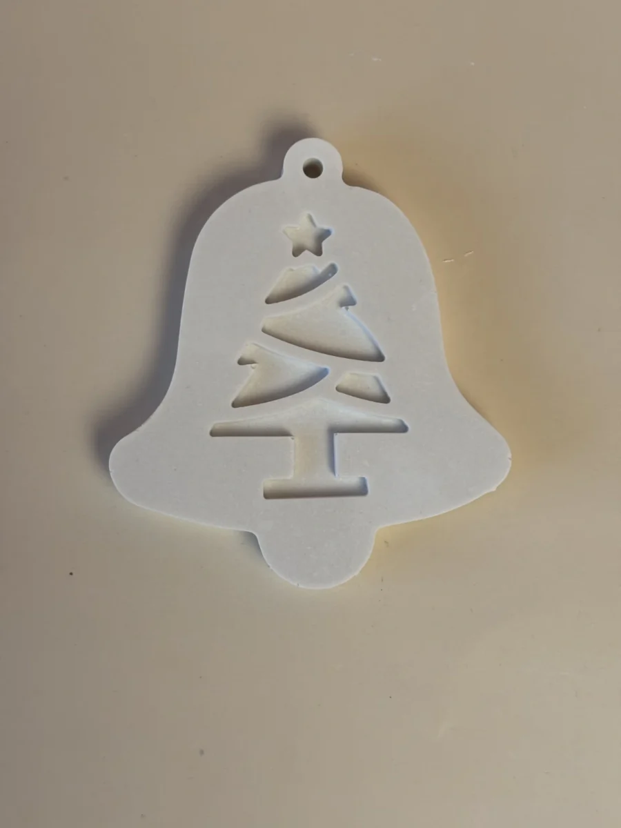 Pendente branco em forma de sino, com motivo de árvore de Natal, estrela e pequeno orifício para pendurar.