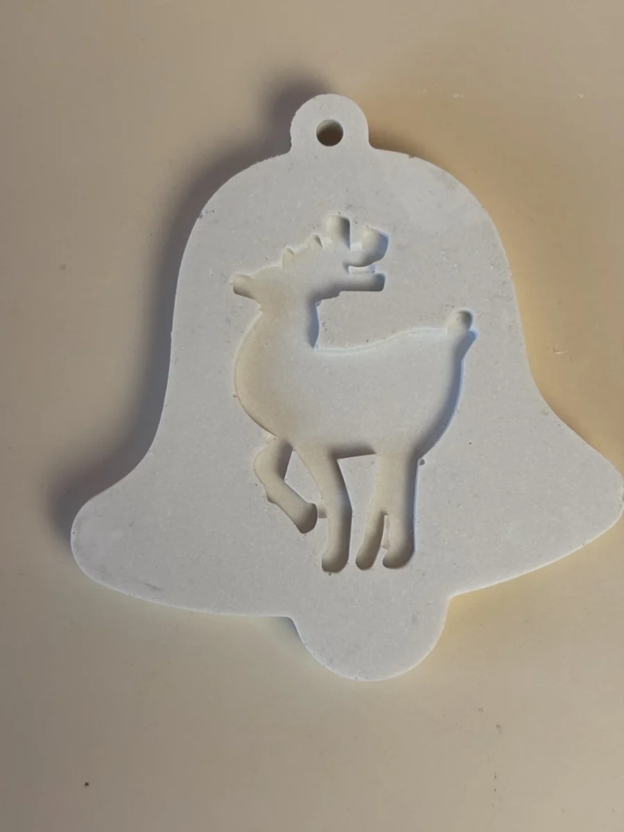 Pendente branco em forma de sino, decorado com uma rena de perfil e com um orifício no topo.