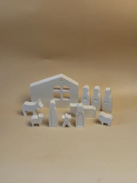 Presépio branco com casa, Sagrada Família, Reis Magos e animais, visto em perspetiva sobre fundo bege.