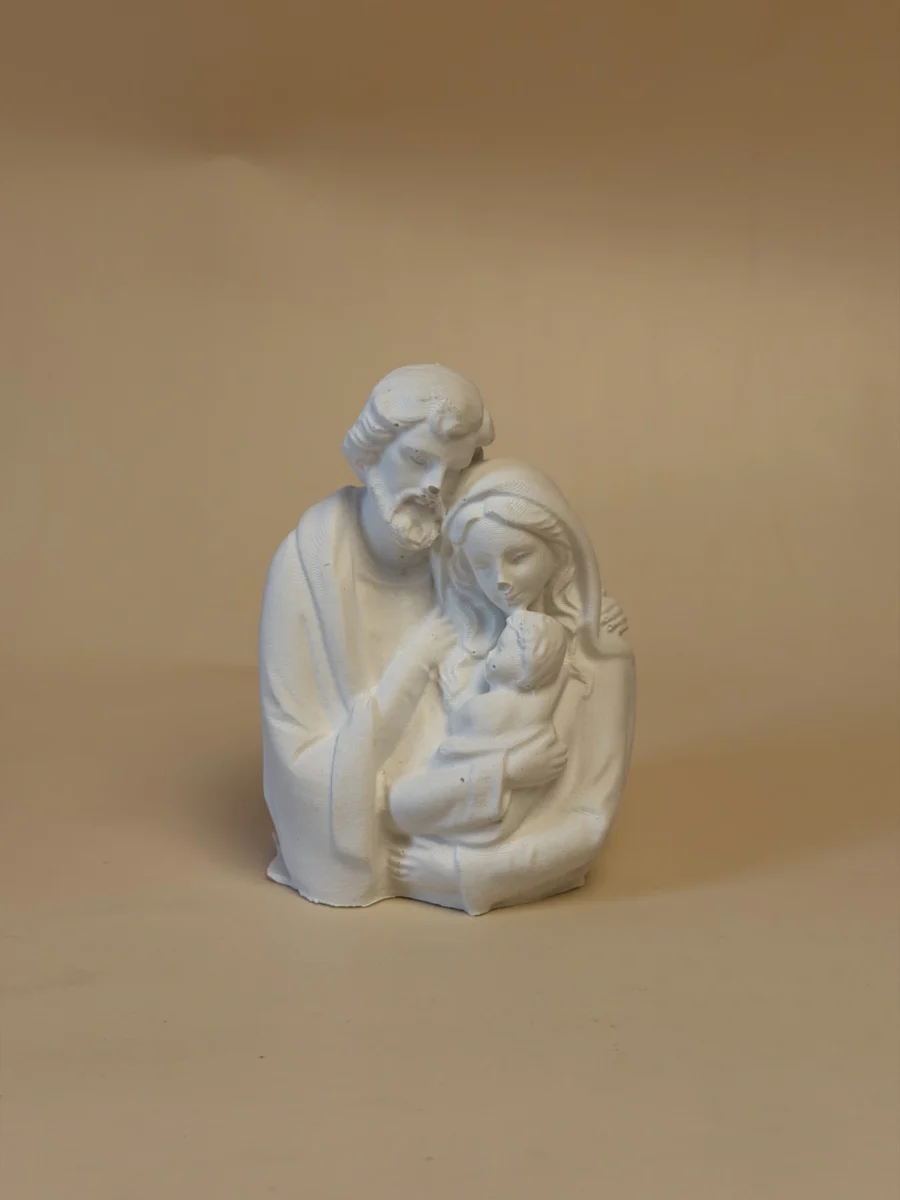 Escultura branca da Sagrada Família, com José junto de Maria e do Menino ao colo, vista de frente.