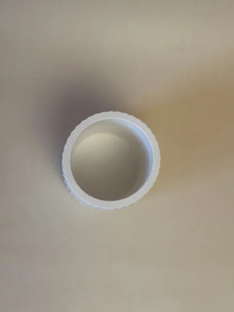 Pote cilíndrico branco visto de cima, com interior liso e rebordo circular canelado.