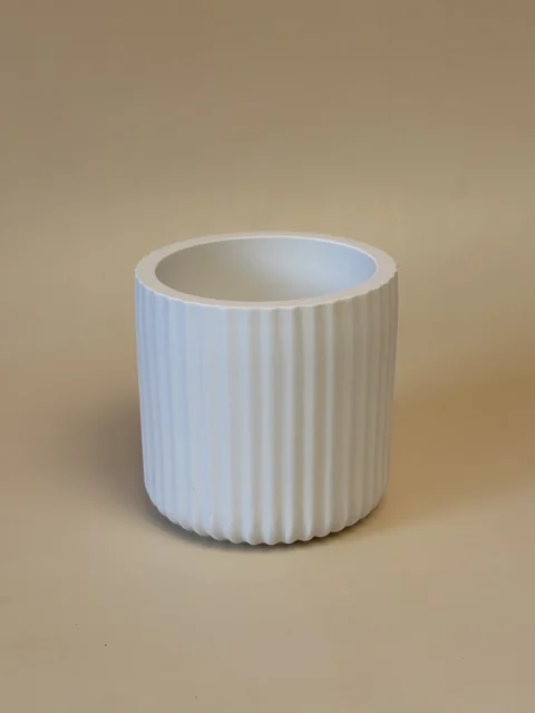 Pote cilíndrico branco com caneluras verticais, visto num ângulo que mostra o interior.