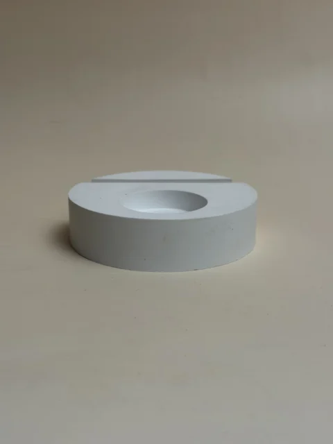 Porta-velas branco circular com ranhura e cavidade para vela, visto de lado